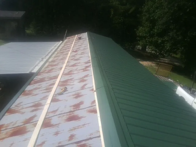 Old rusted panels beside newly installed green metal roofing — Wind Damage Roof Repair by Roofing Brothers in Valley Park