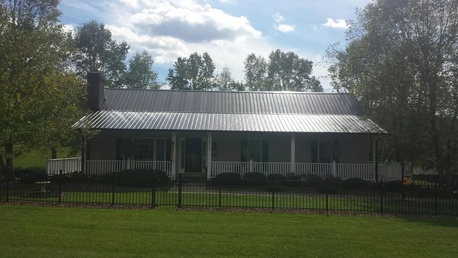 Gray metal roof on a brick ranch with a full width front porch — Gutter Guard Installation work by our crew in Valley Park